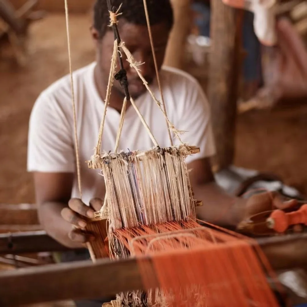 Un tisserand au métier, fils orange tendus