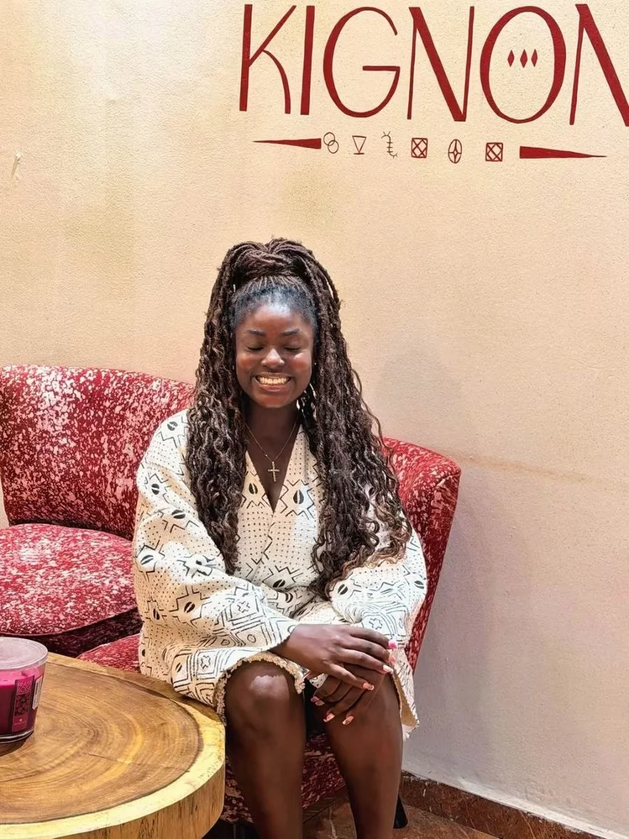 Une cliente assise sous le nom Kignon peint au mur de la boutique