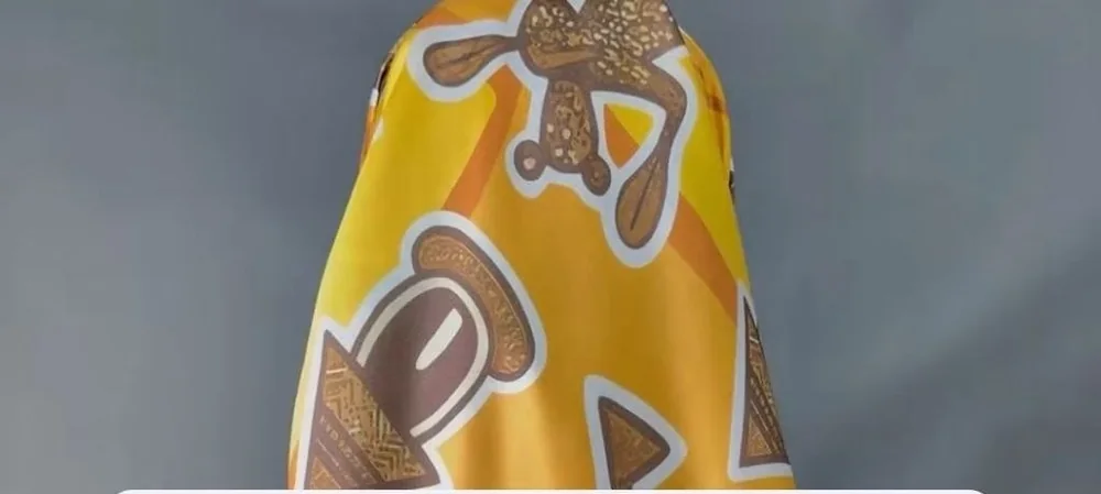 Carré de soie jaune aux motifs marron, noué sur la tête